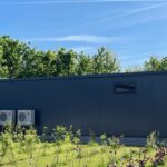 Außenansicht eines Powerhouses: Rechts im Bild die Zugangstüren zum Transformator und zur Mittelspannungsschaltanlage, links an der Gebäudewand die Klimaanlagen zur Kühlung der Batteriesysteme. Quelle: Sonepar Deutschland GmbH